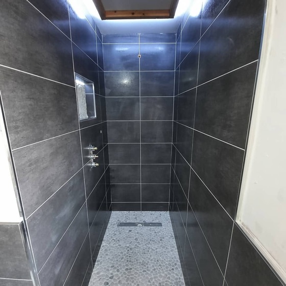 Dark grey wall tile in a shower enclosure with a speckled terrazzo effect tray