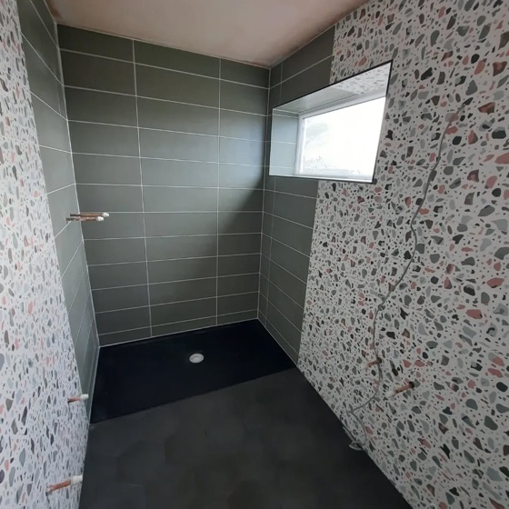 Green subway tile beside a patterned wall tile, with a dark tray and hexagon floor