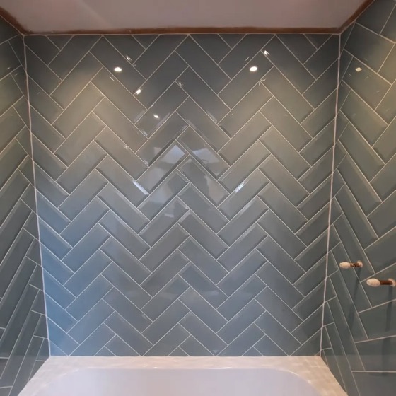 Grey gloss metro tile laid herringbone above a bath