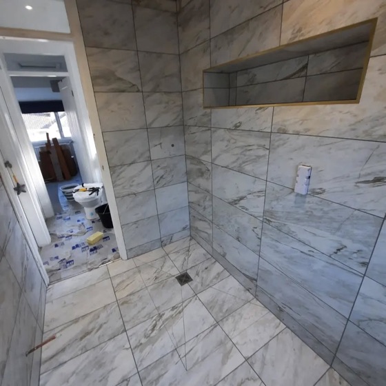 Marble effect porcelain in a wetroom, finished with brass trim