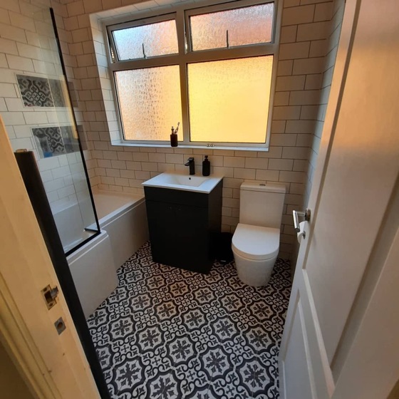 Patterned encaustic style floor tile in a cloakroom with a dark vanity unit