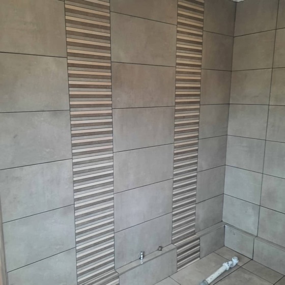 Ribbed white feature tile run in a vertical panel between plain wall tile
